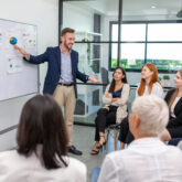 business team male and female colleagues talking at work share ideas with chart on board, Happy young presentation colleagues work together on board.