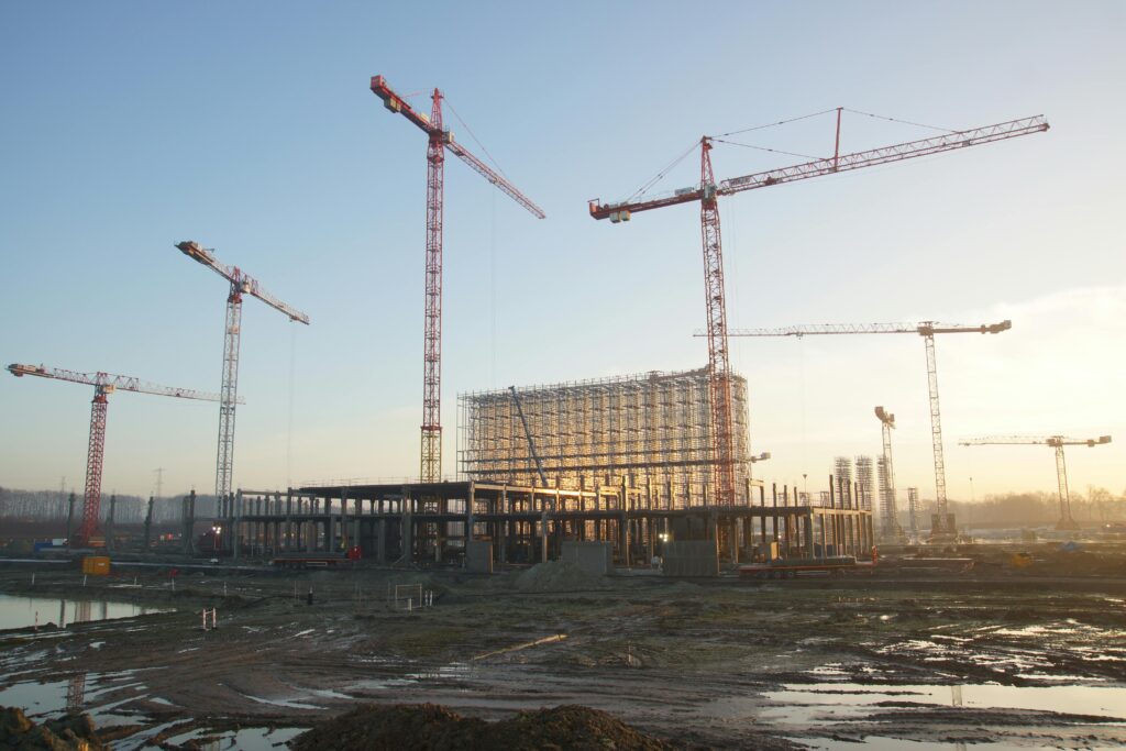 Wide view of a construction site with cranes and building framework at sunset. Industrial landscape.