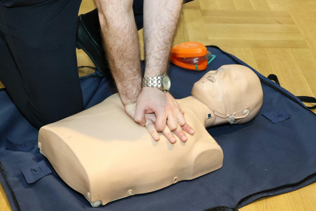 Hands performing CPR on a training dummy using realistic techniques indoors.